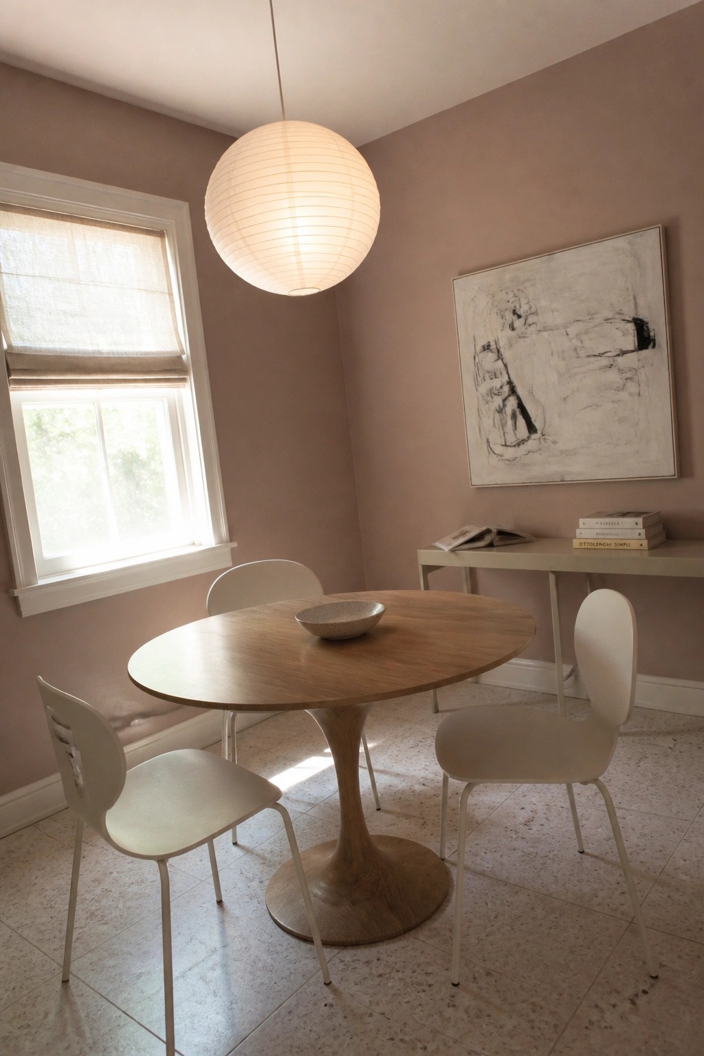 Soft rose beige walls in a small dining room with a round wooden table.