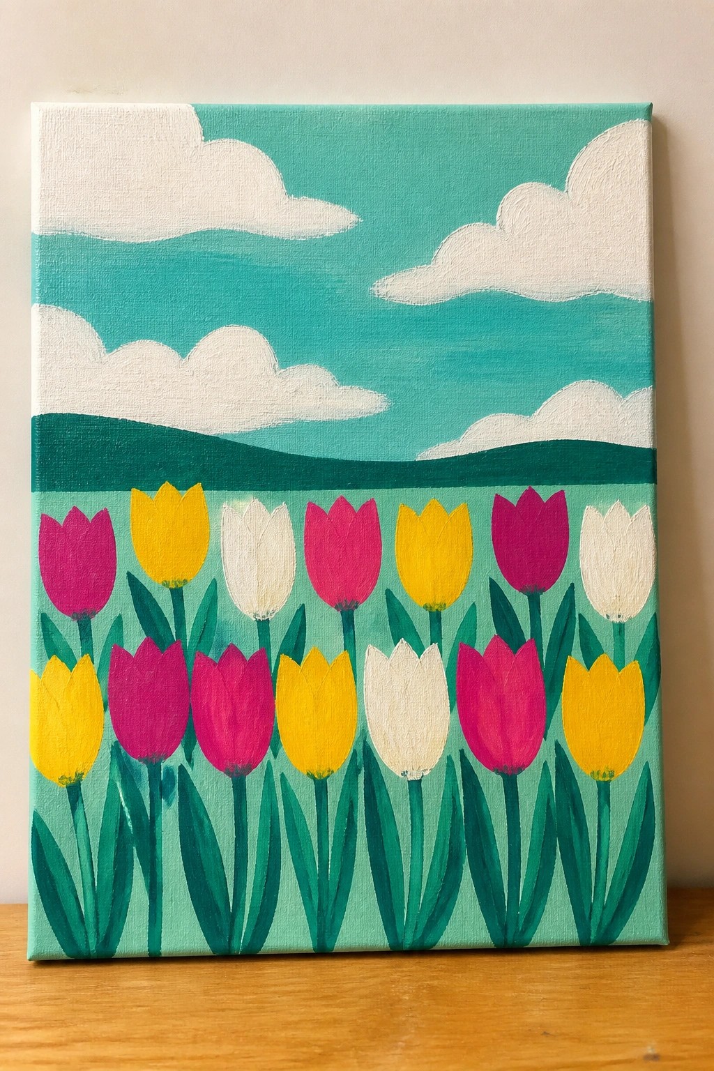 Colorful painting of pink, yellow, and white tulips with green stems under a teal sky with clouds.