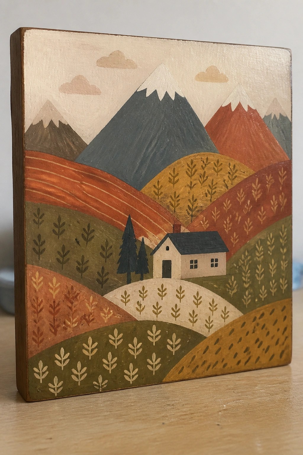 Oil painting of a small house set among layered hills and mountains with patterned foliage in greens, oranges, and reds.