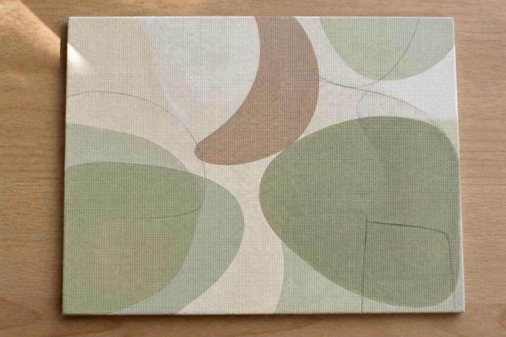 Abstract painting of overlapping green circles and ovals on canvas atop wood.