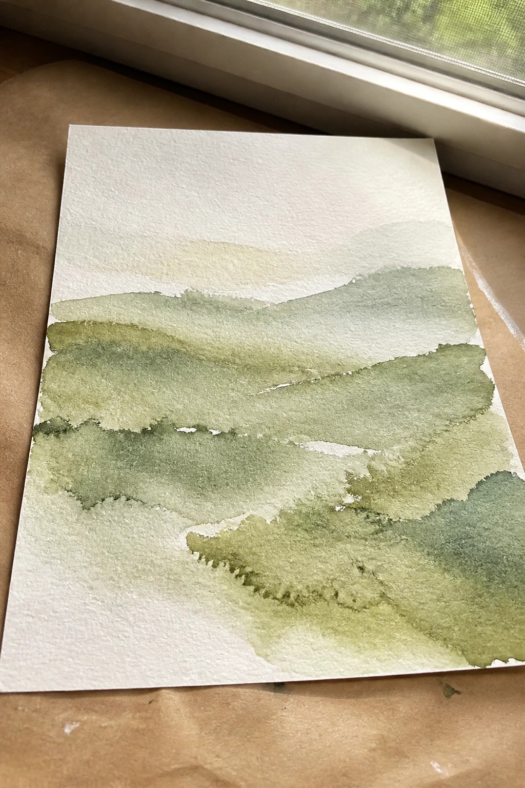 Watercolor landscape of layered green hills with soft blended washes