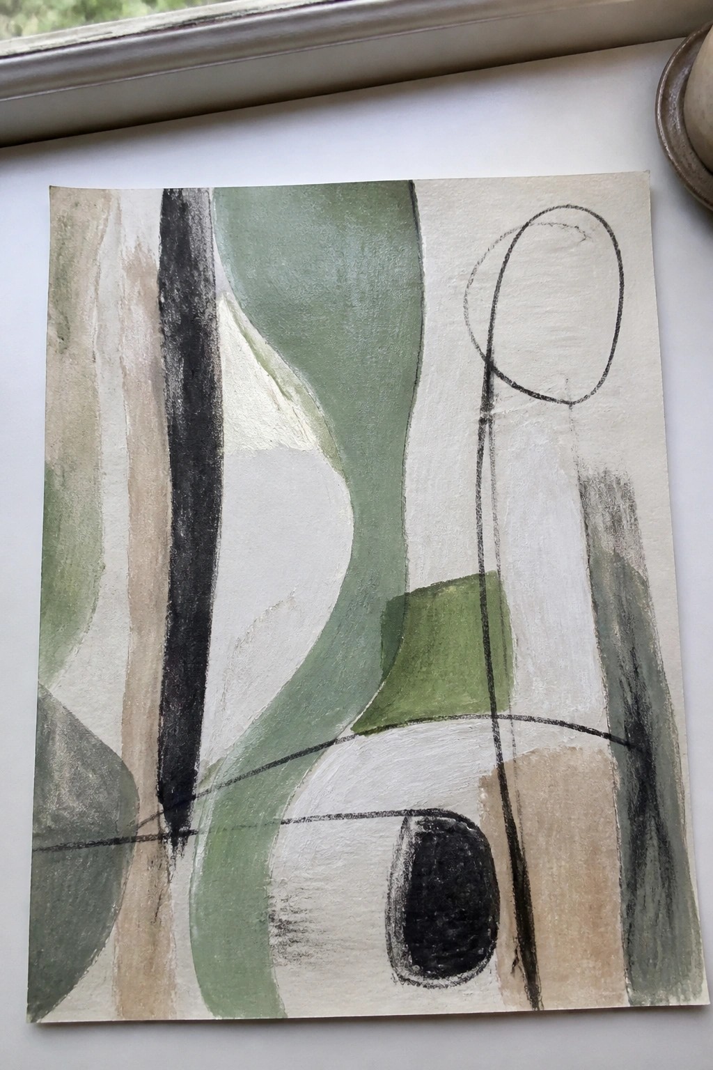 Abstract painting with green, black, white shapes and lines on paper by window