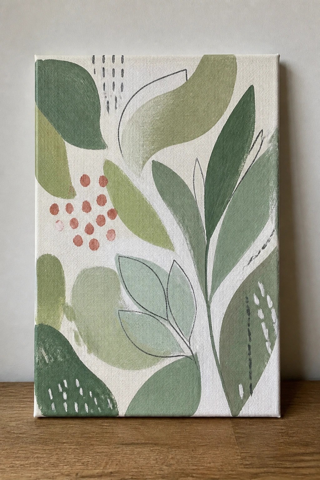 A rectangular canvas painting featuring abstract green leaves of various shades with black outlines and a cluster of coral-colored dots on a white background.