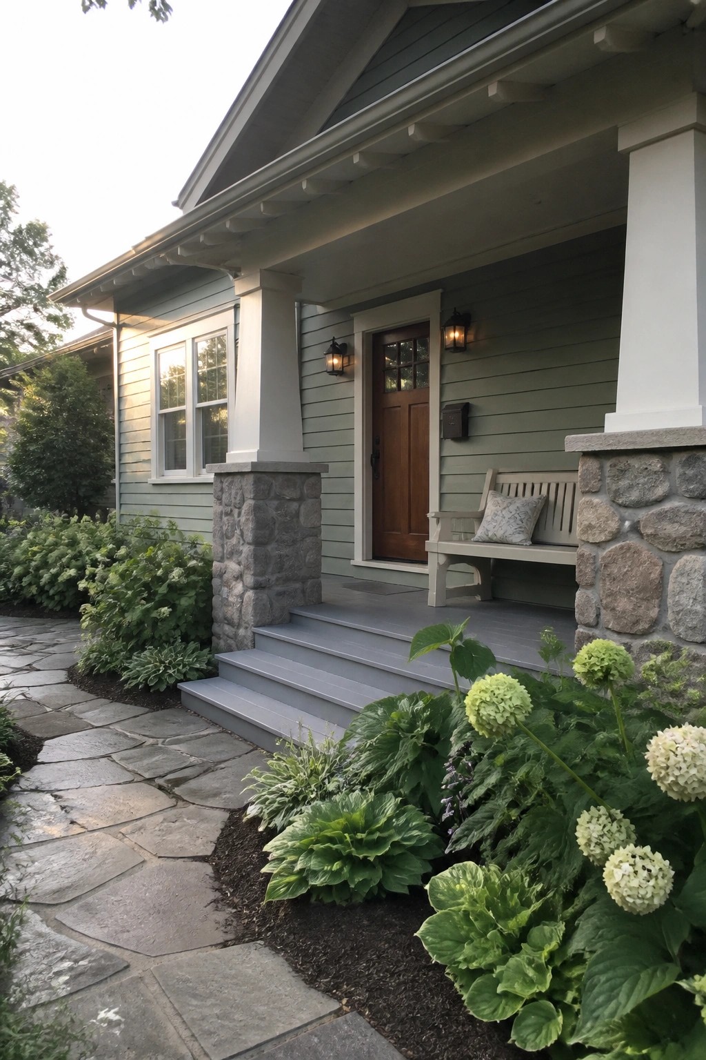House exterior with soft sage green siding next to stone pillars and steps.