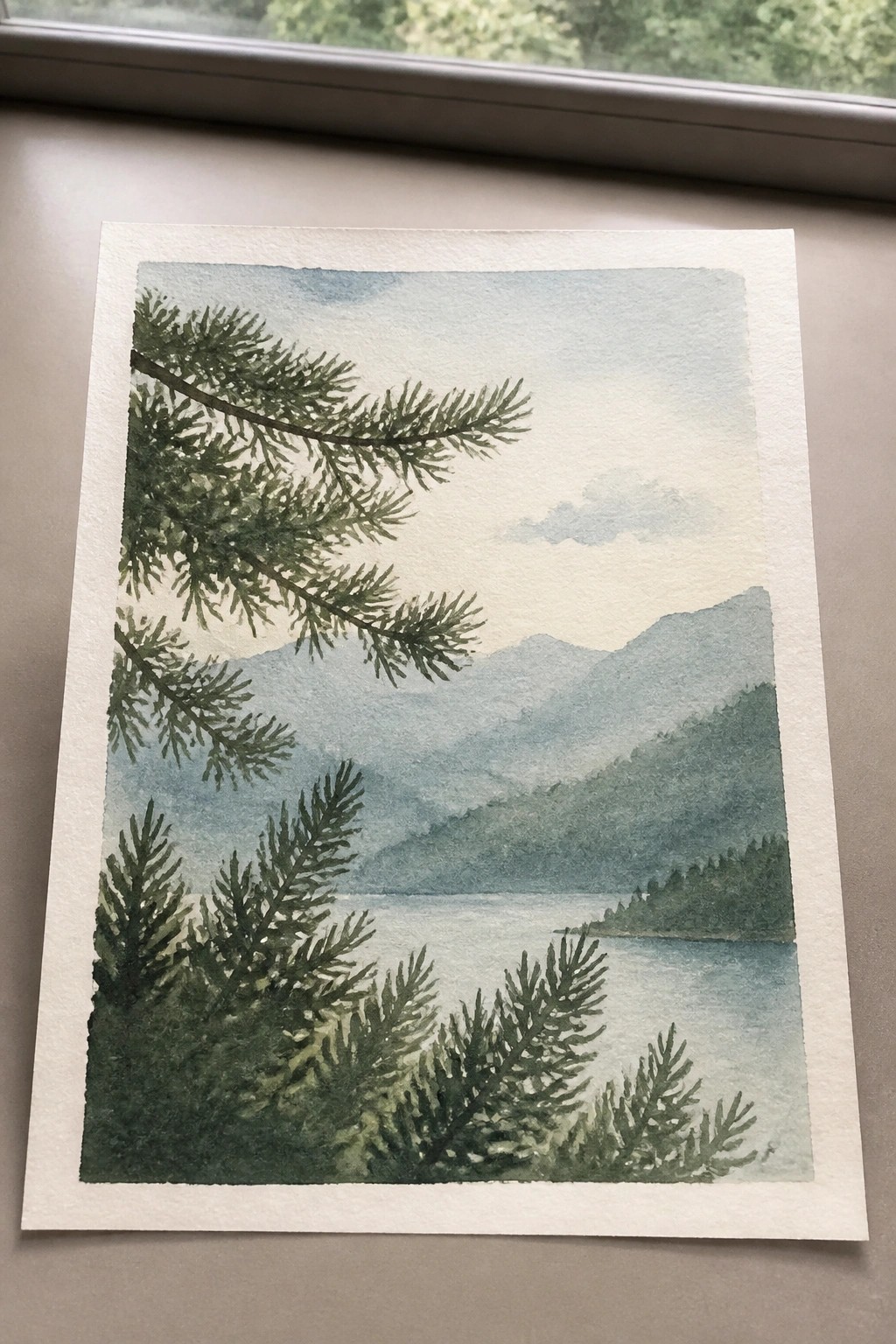 Watercolor painting of pine trees framing a calm lake with misty mountains beyond