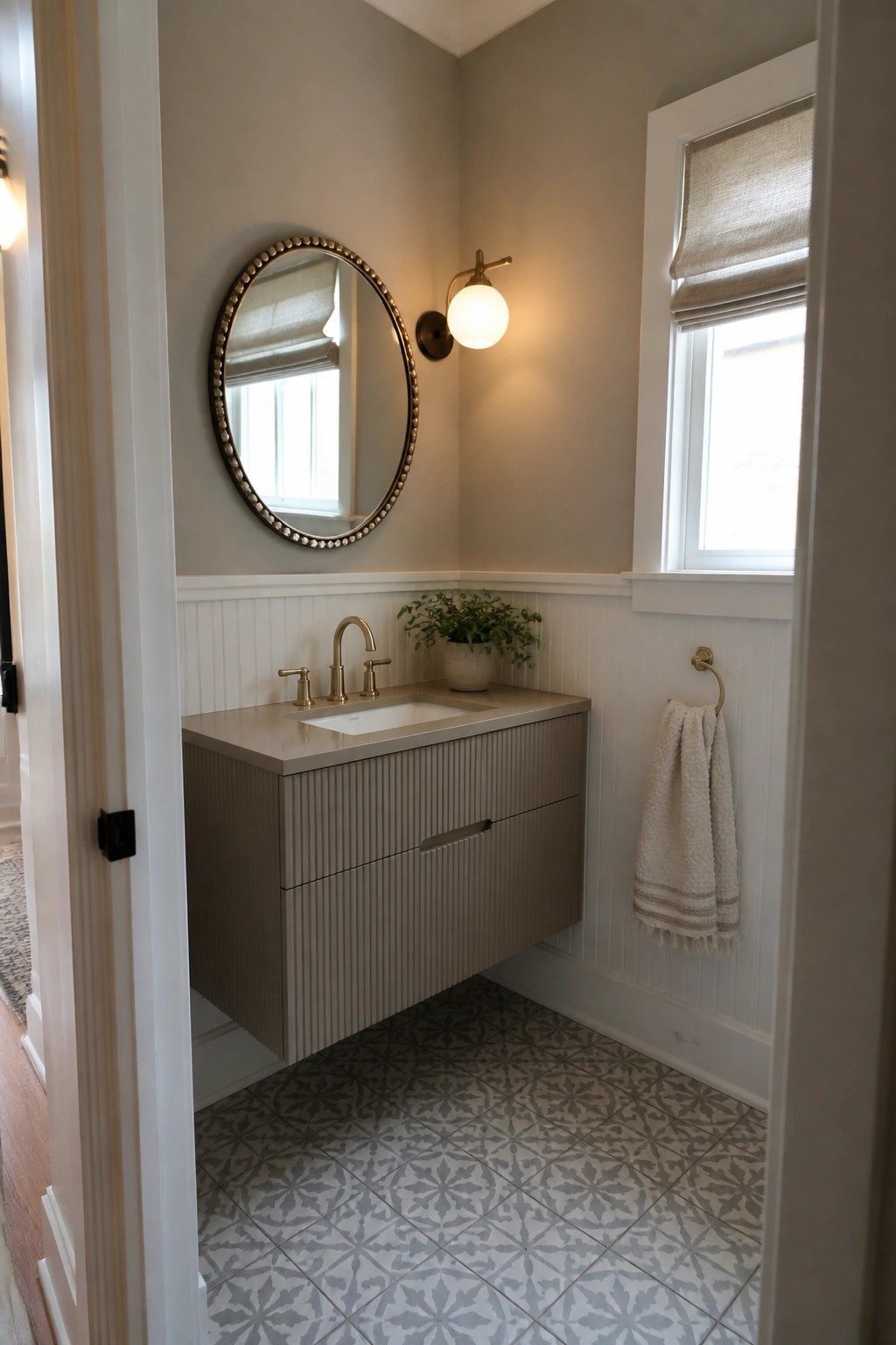 A small bathroom with soft greige walls above white wainscoting and a floating vanity.