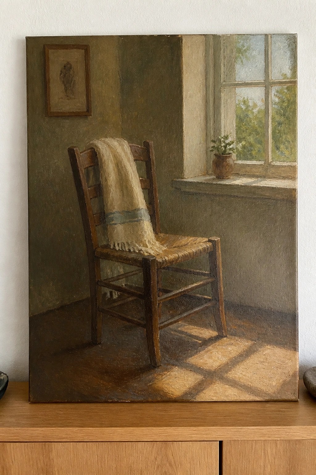 Wooden chair with draped cloth in sunlit room by window with potted plant