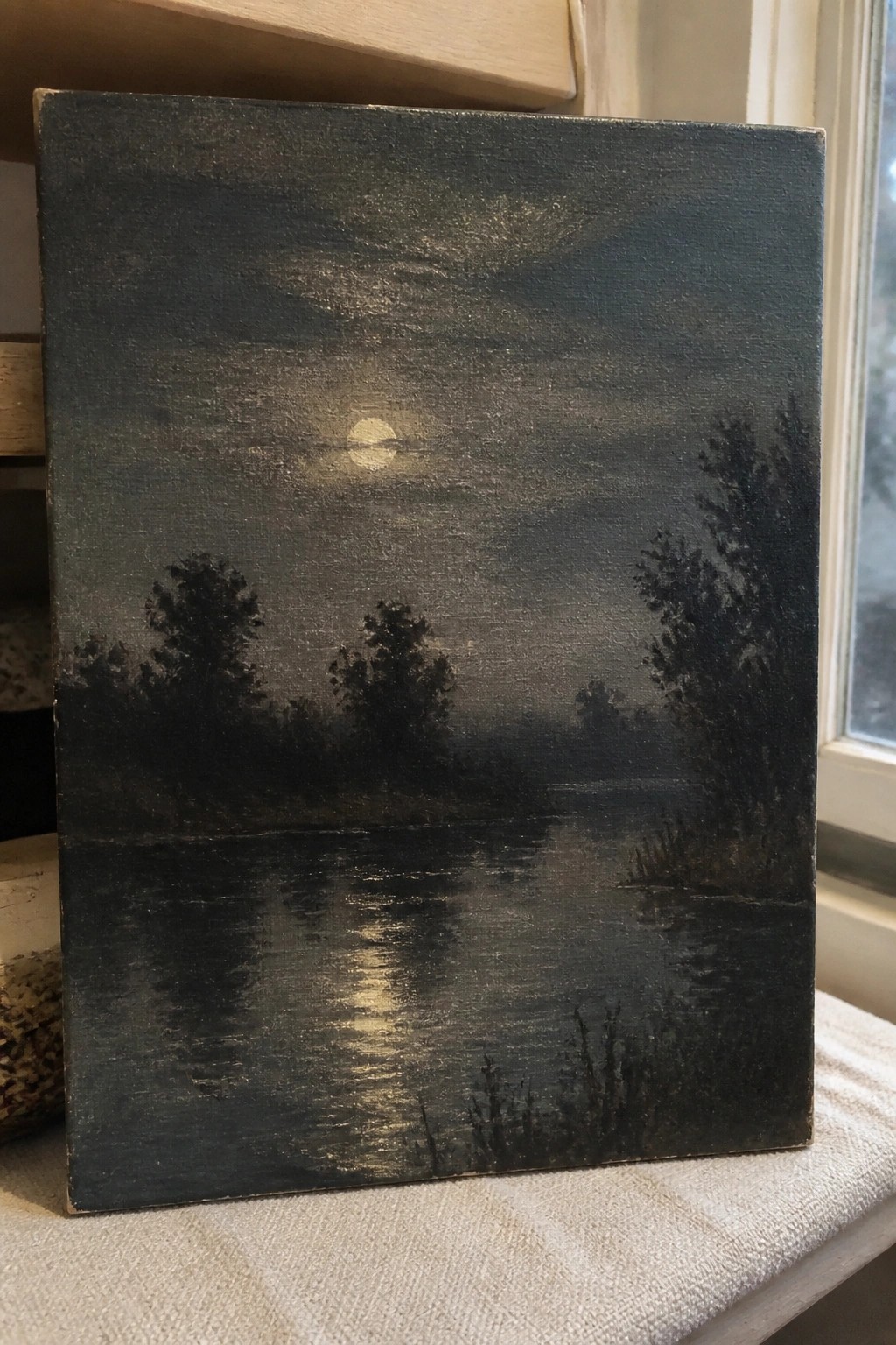 Moonlit river landscape painting with dark silhouetted trees and glowing water reflection.