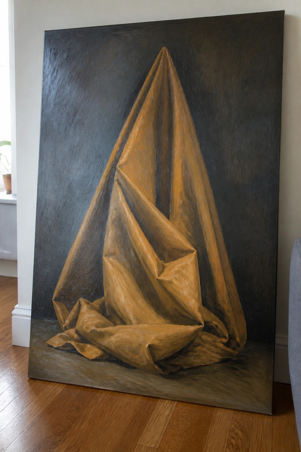Large realistic painting of wrinkled brown fabric forming a tall peak on dark background.