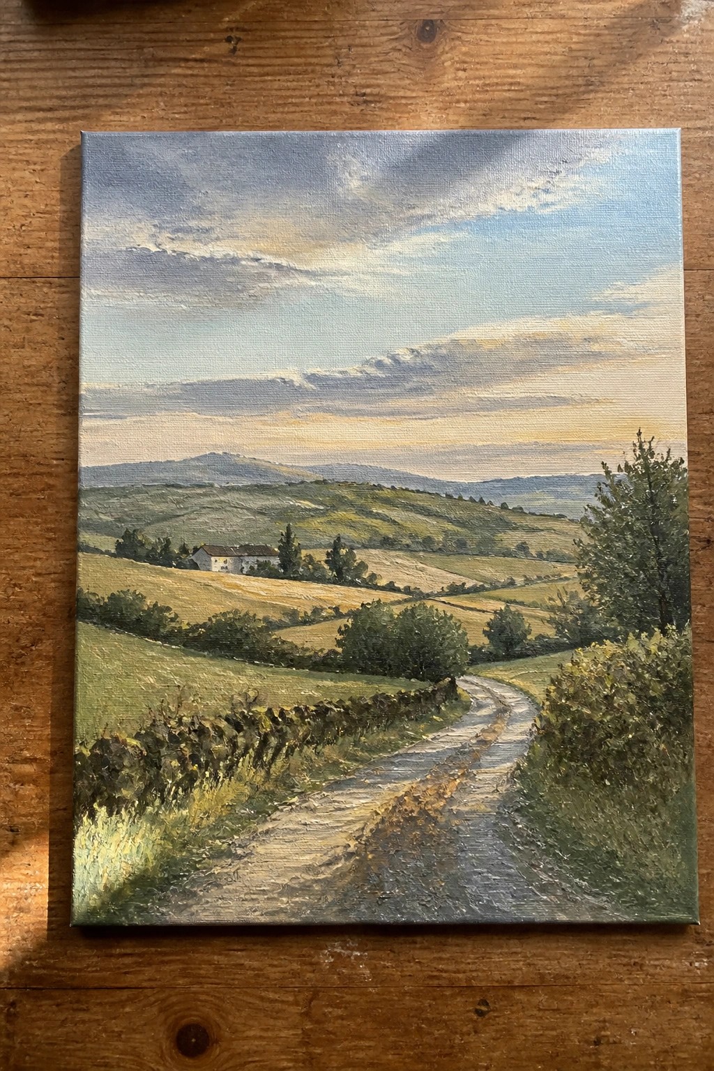 Oil painting of winding dirt road curving through rolling green hills with farmhouse.