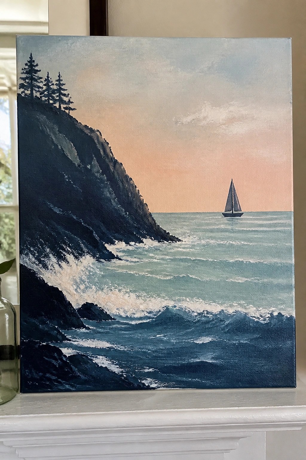 Seascape painting of cliffs with trees, crashing waves, and distant sailboat at sunset.