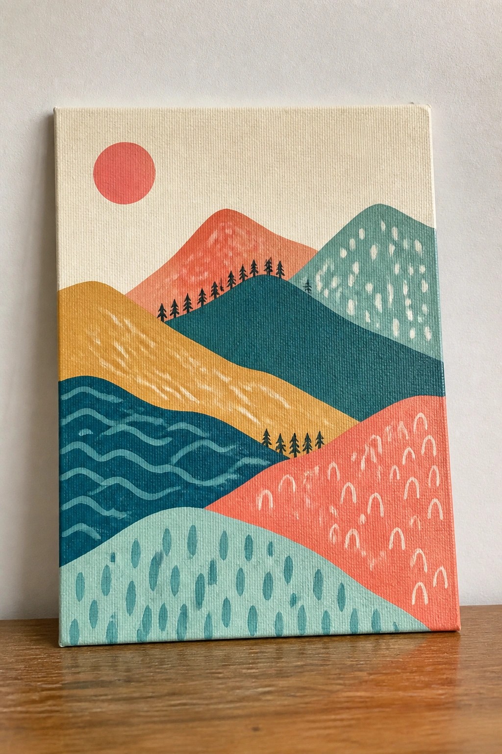 Colorful abstract canvas painting of layered mountains with red sun and pine trees.