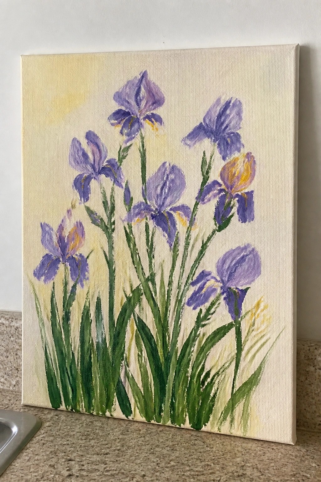 Painting of purple irises with yellow accents and green stems on canvas.
