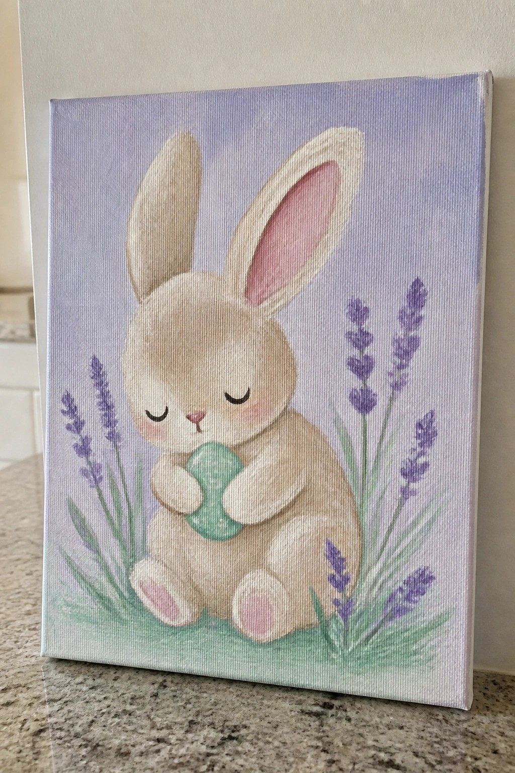 Pastel painting of sleeping bunny holding green egg amid purple lavender flowers on canvas