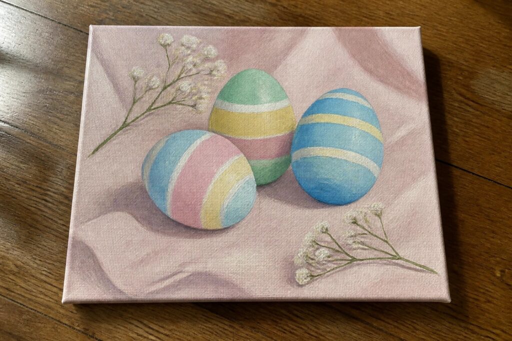 Three pastel striped Easter eggs on pink fabric with white flowers