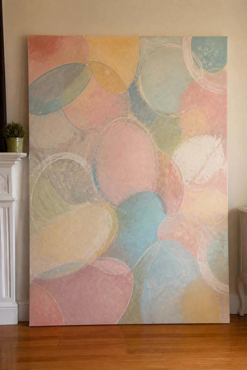 Large abstract painting with soft pastel overlapping circles in room with wooden floor