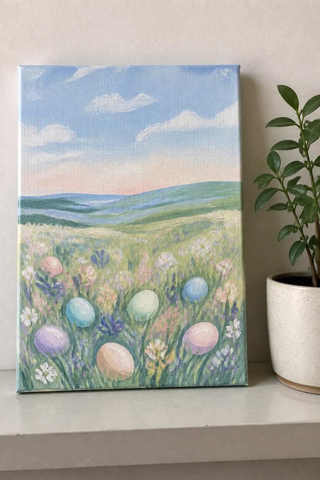 Pastel painting of wildflower meadow with colorful Easter eggs, hills, and potted plant