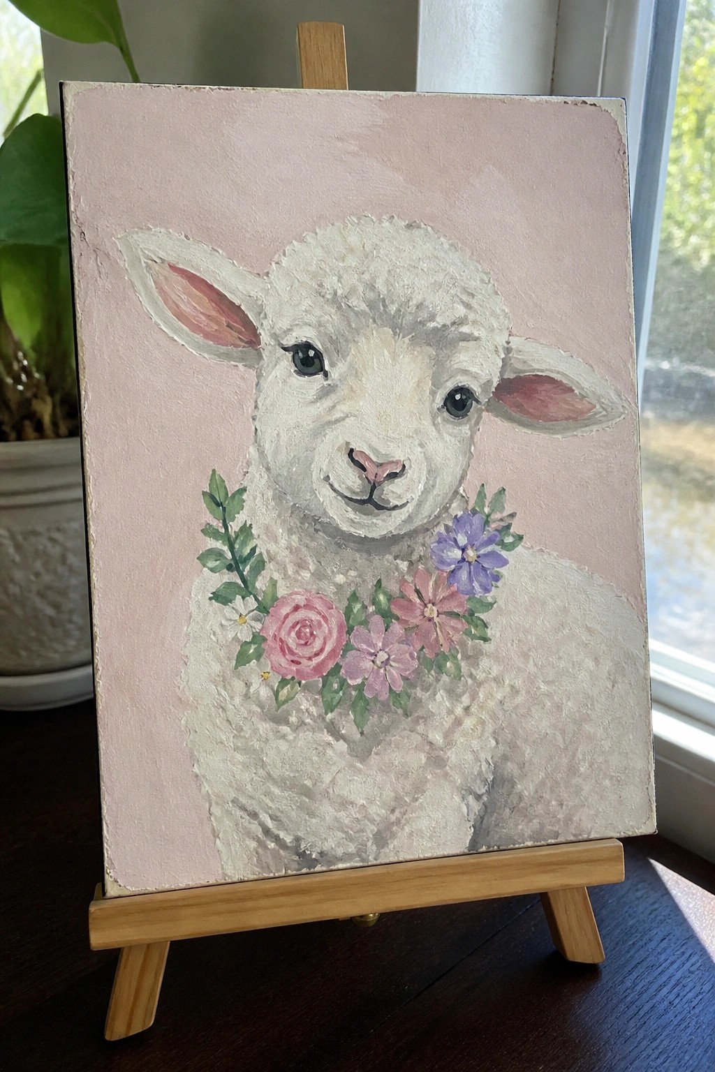 White lamb with pink rose and purple flowers on soft pink background, wooden easel
