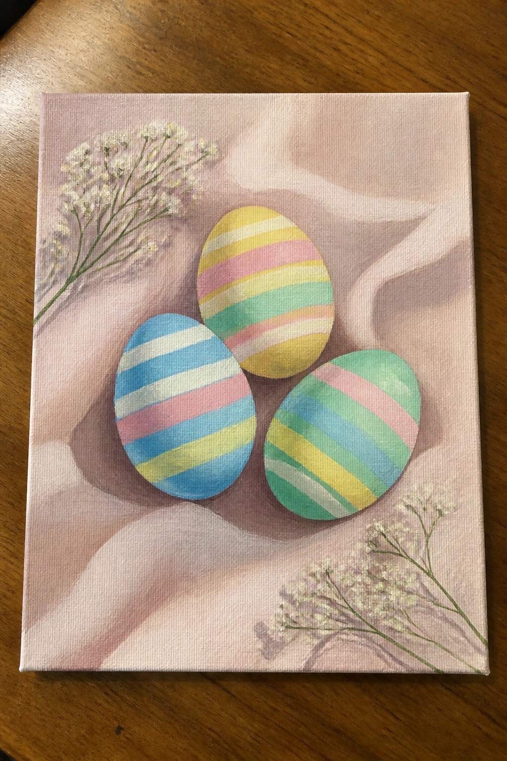 Three pastel striped Easter eggs on pink fabric with white flowers