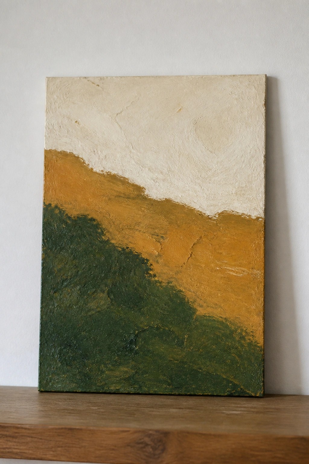 Abstract painting with thick white, orange, and green textured layers on wooden shelf