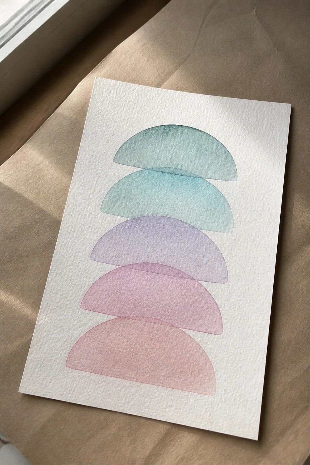 Vertical stack of overlapping watercolor semicircles in teal to pink gradient on white paper.