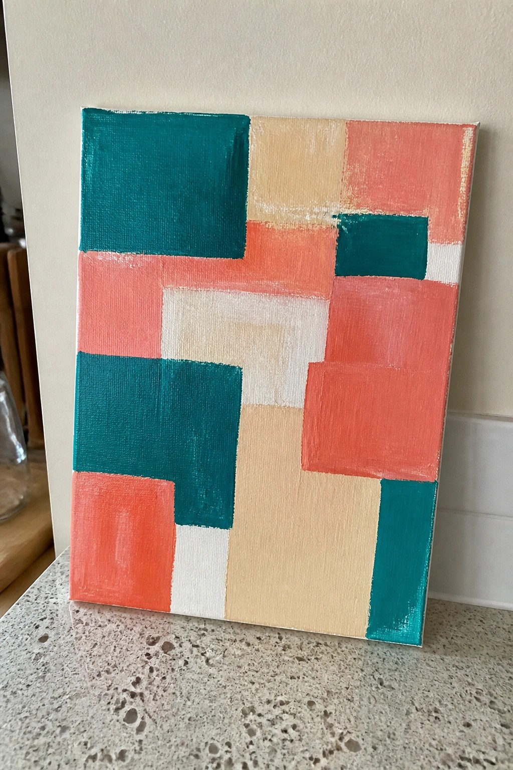 Abstract geometric painting with teal, coral, beige, and white blocks on canvas.