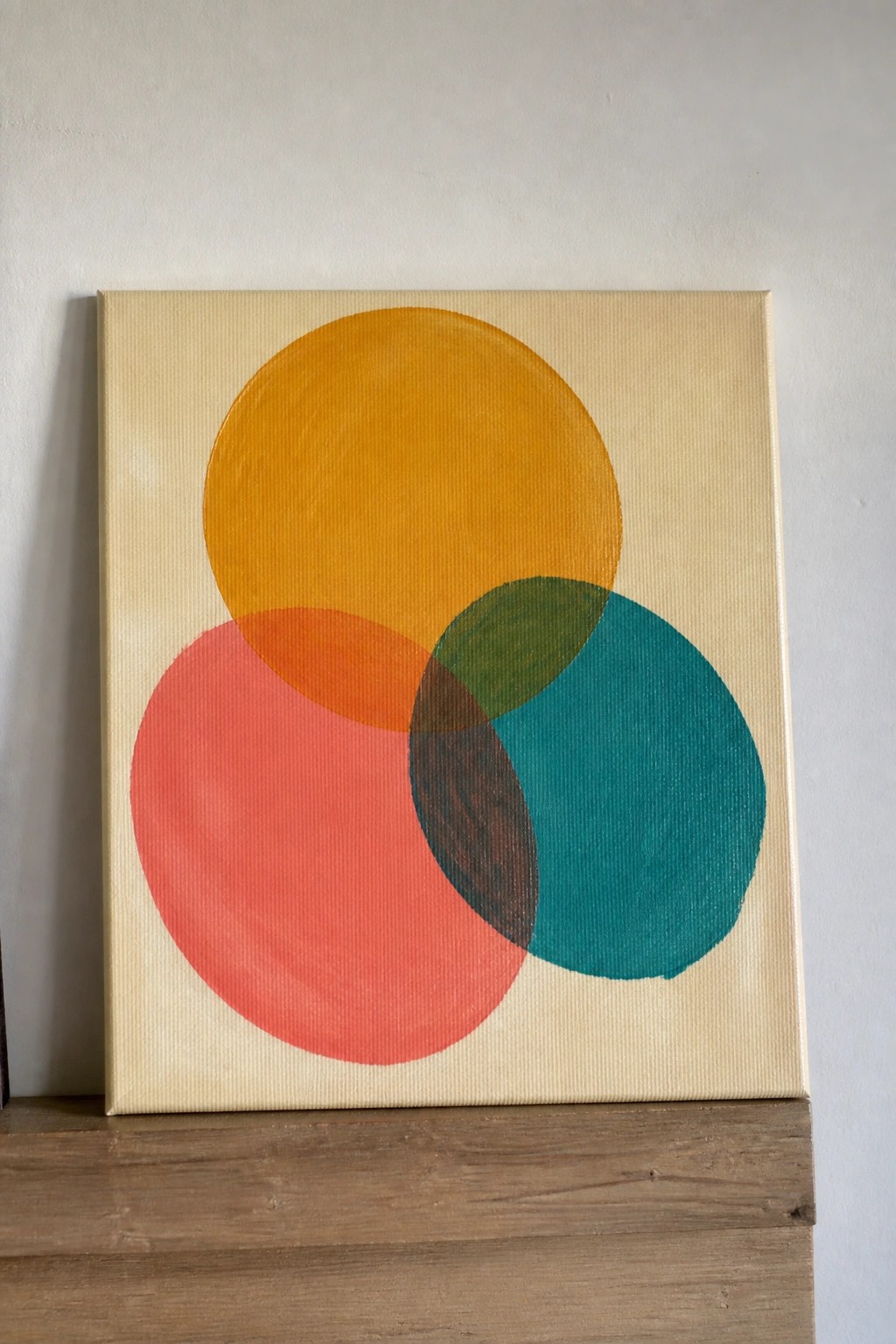 Abstract painting with overlapping yellow, red, and teal circles on beige canvas.