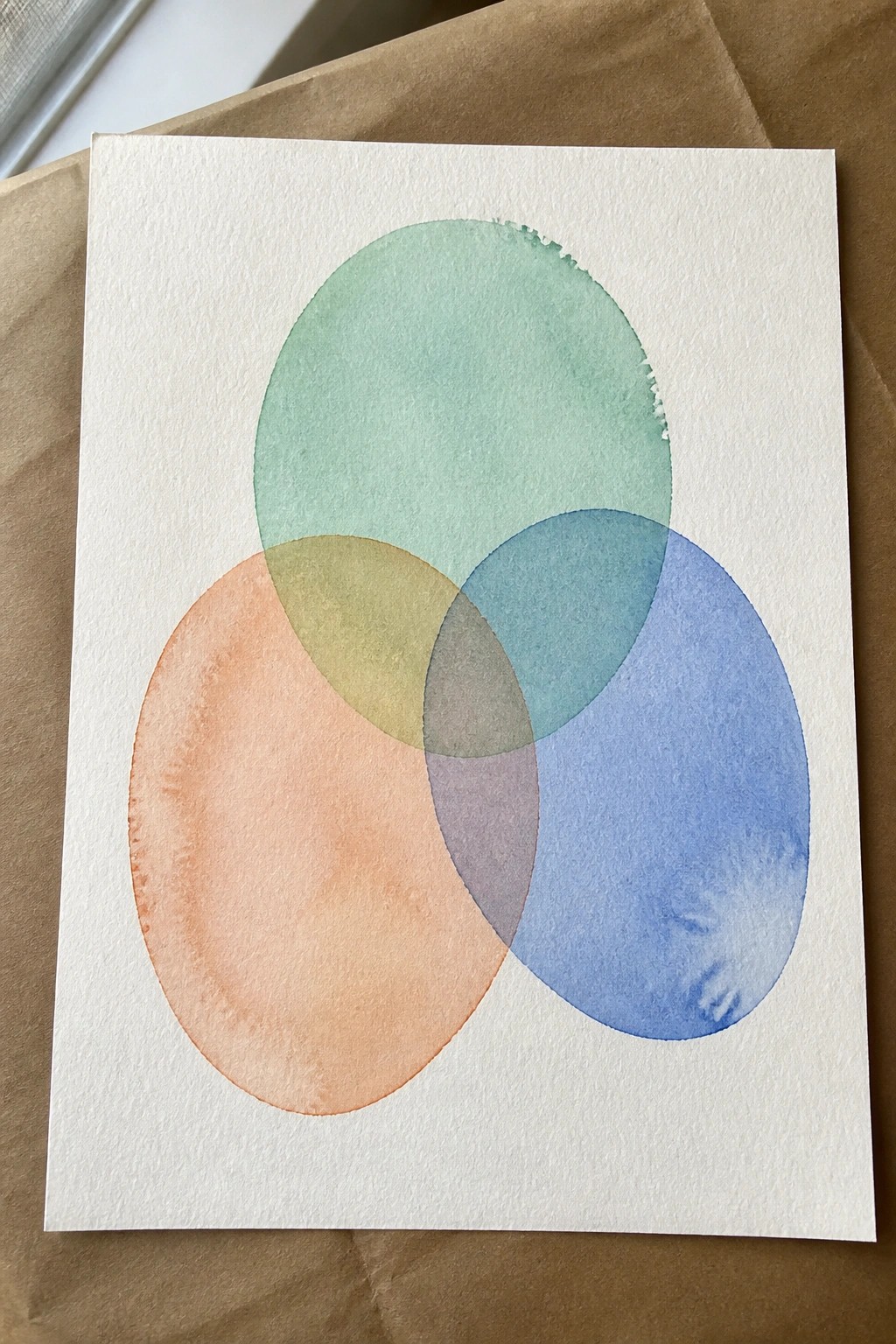 Watercolor painting of three overlapping translucent circles in coral, green, and blue.