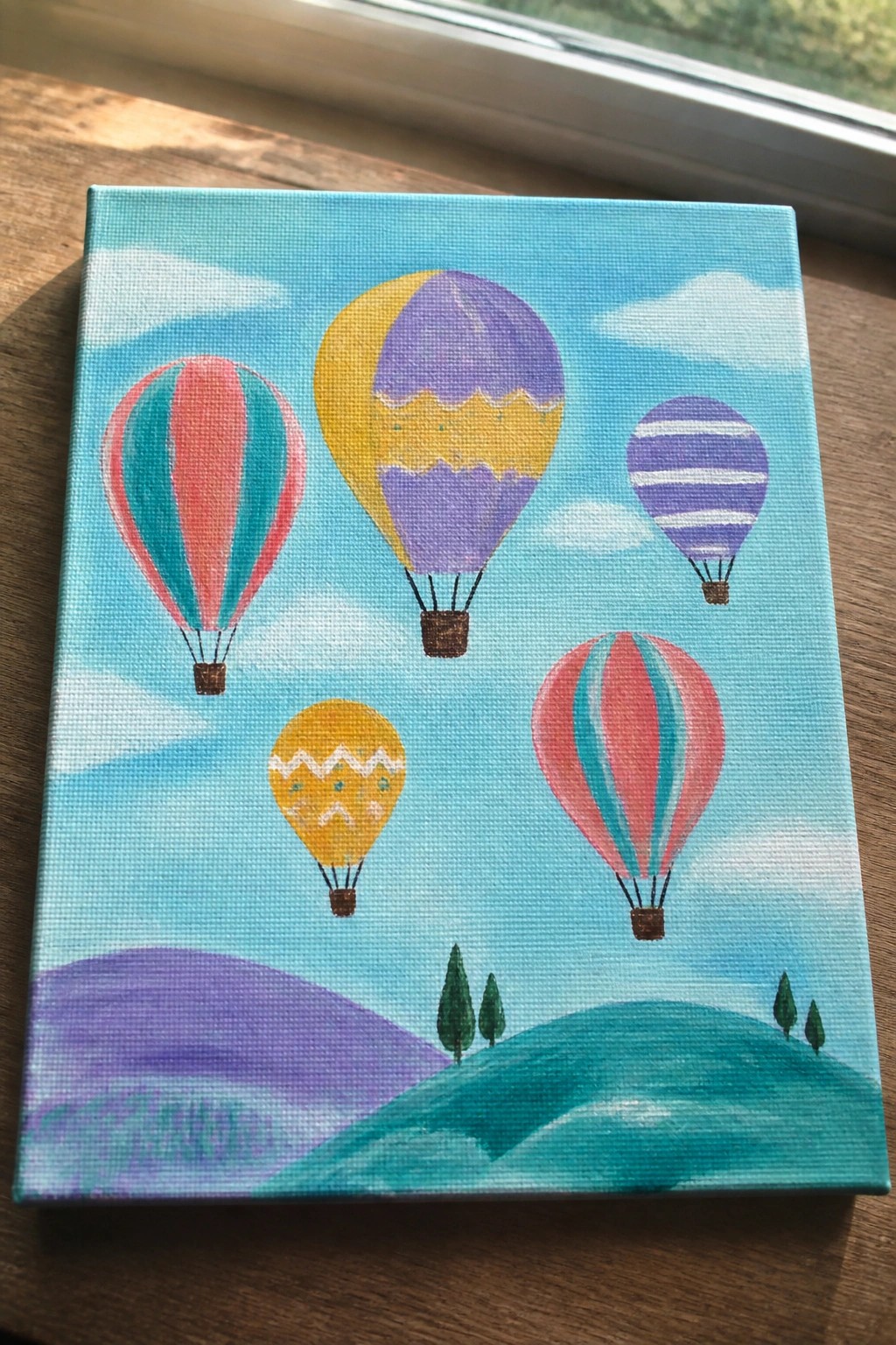 Colorful hot air balloons floating above rolling purple and green hills with trees.