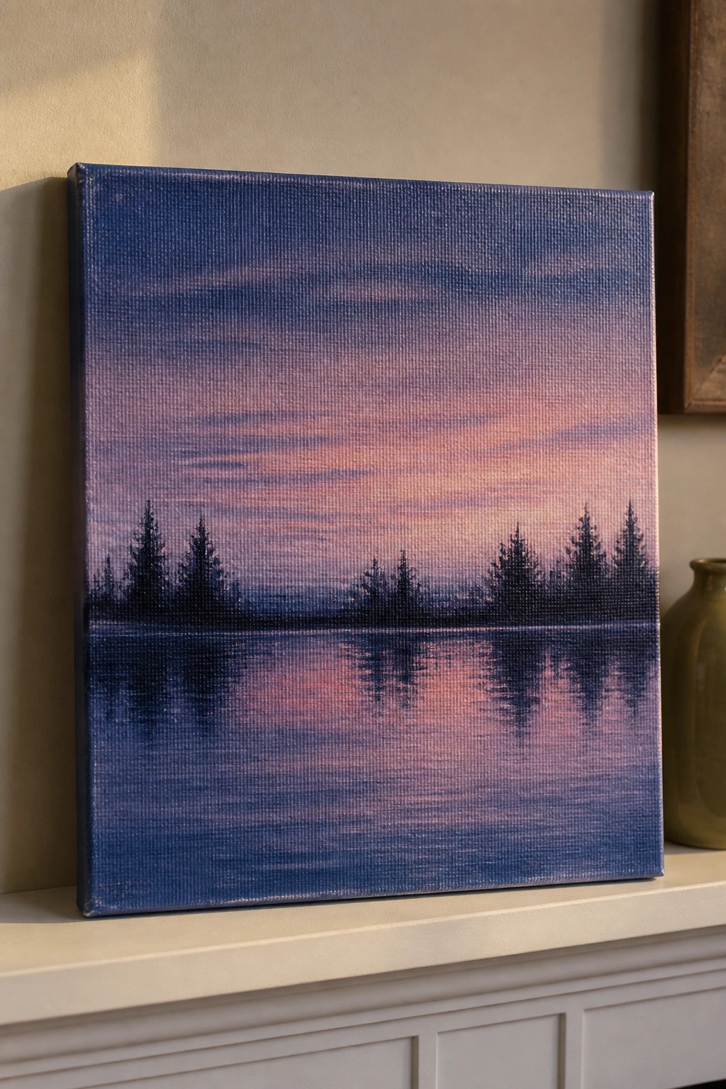 A canvas painting of a lake at sunset with silhouetted pine trees and their reflections in the water under a gradient sky.