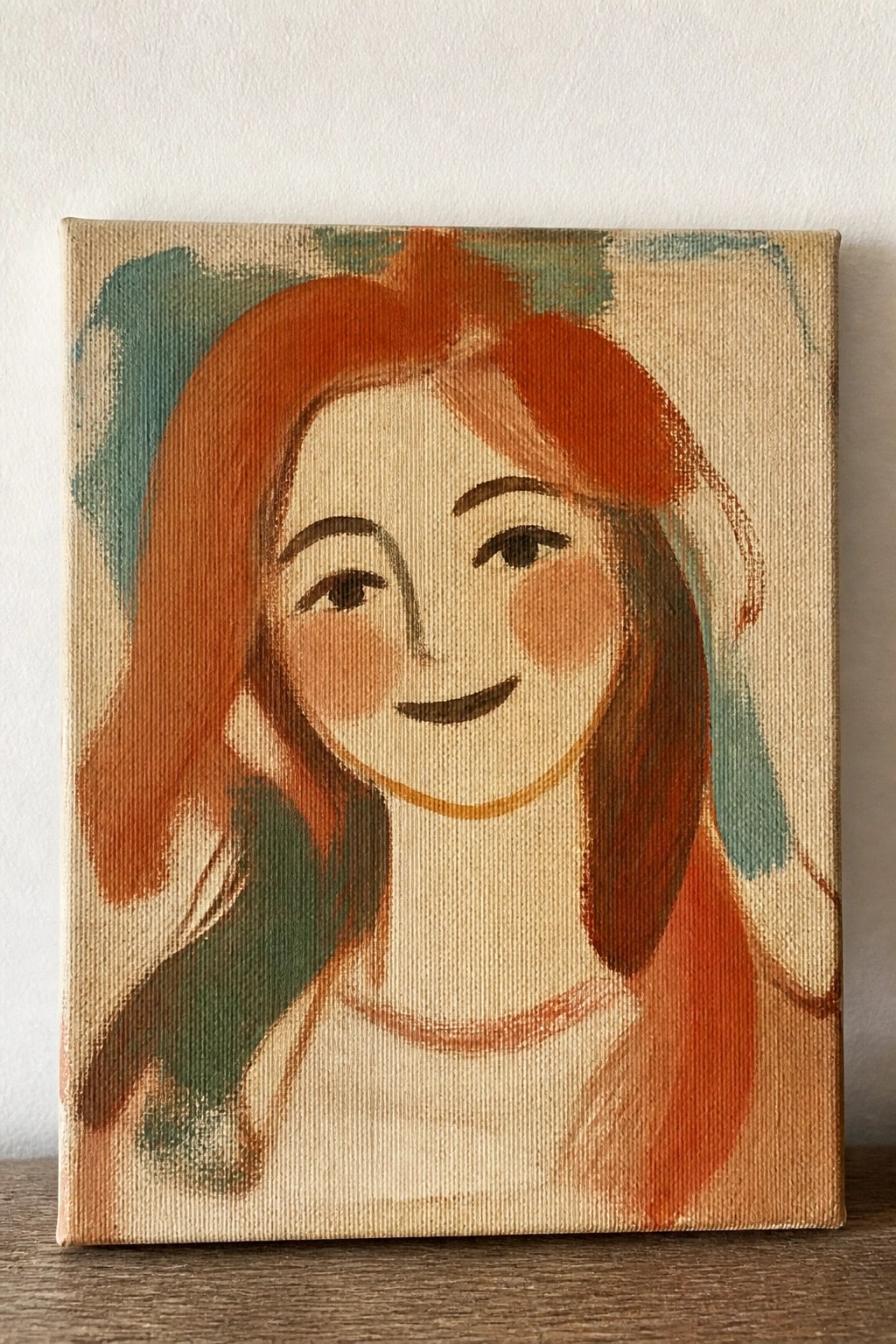 Painting of smiling red-haired woman with rosy cheeks on canvas with teal accents.