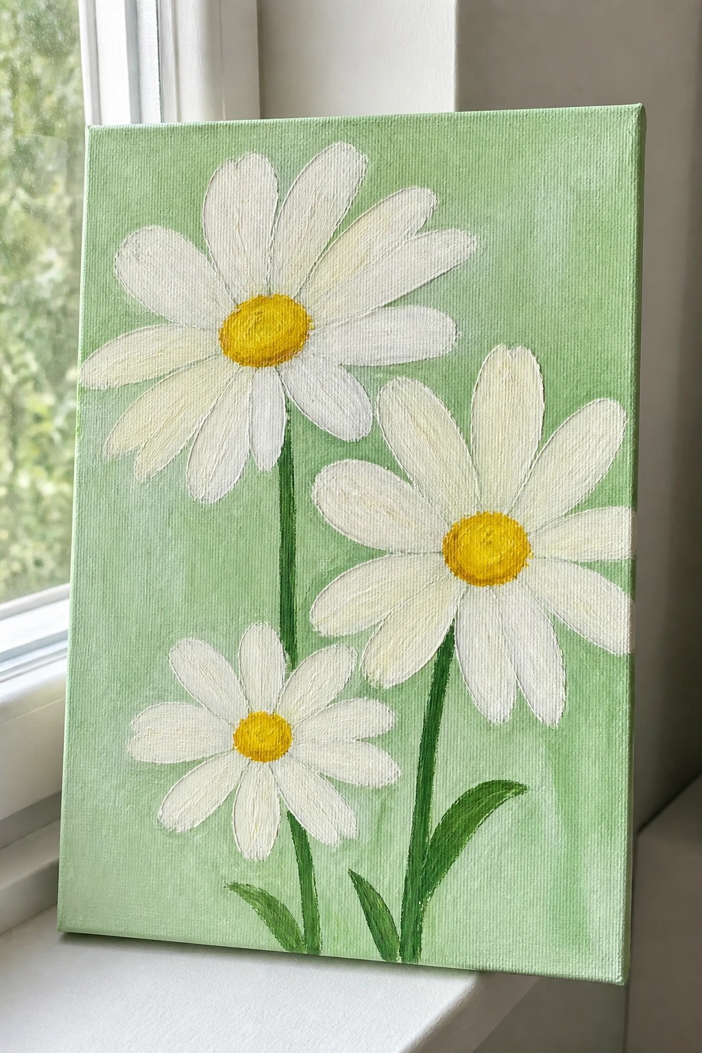A canvas painting of three white daisies with yellow centers and green stems on a light green background.