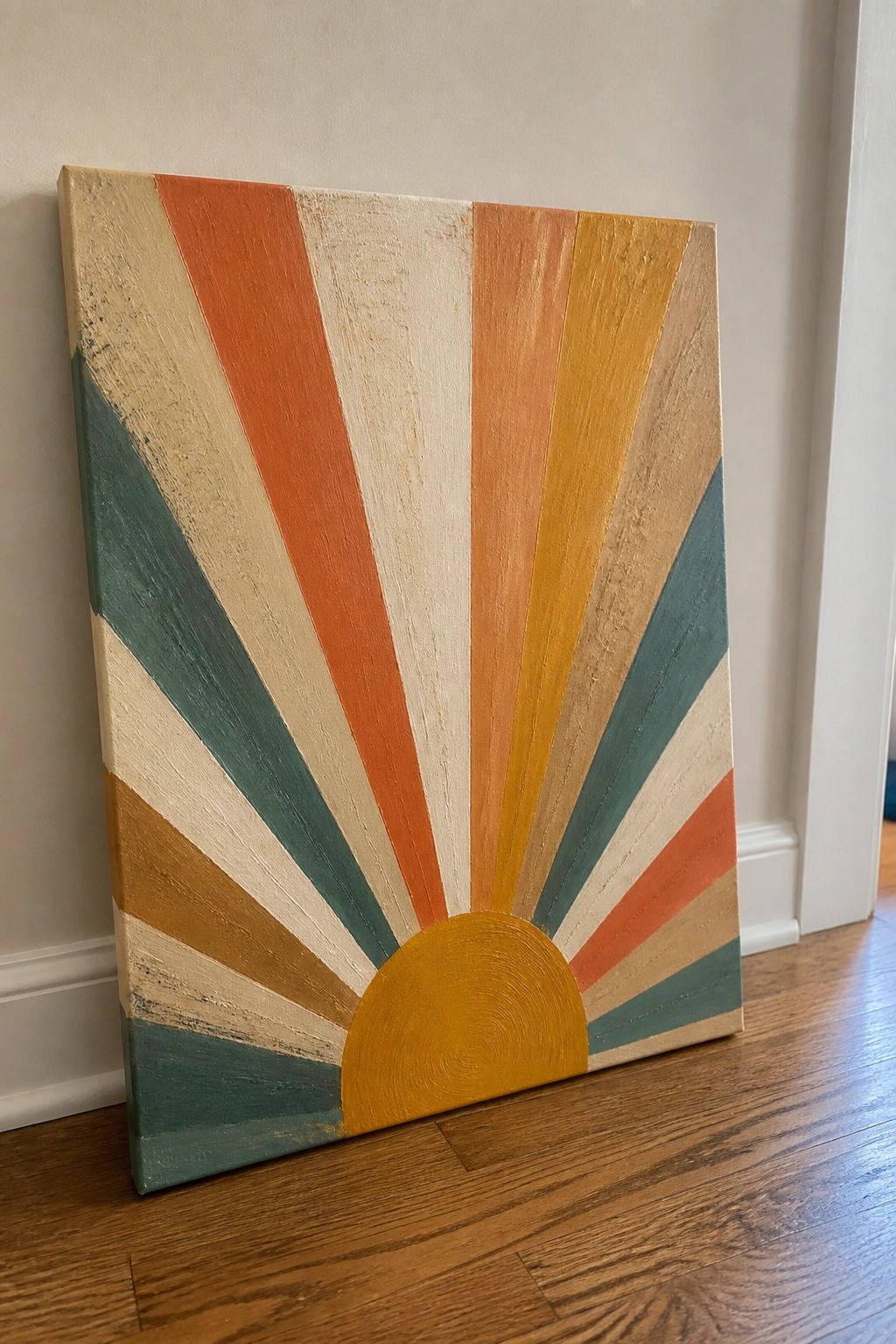Retro sunburst canvas painting with orange teal yellow rays on wood floor