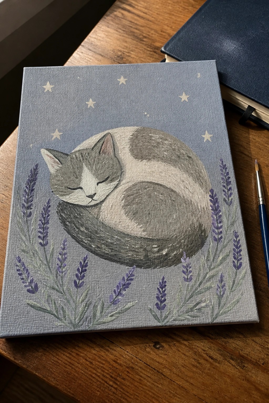 Gray cat curled sleeping on blue canvas with stars and purple lavender sprigs