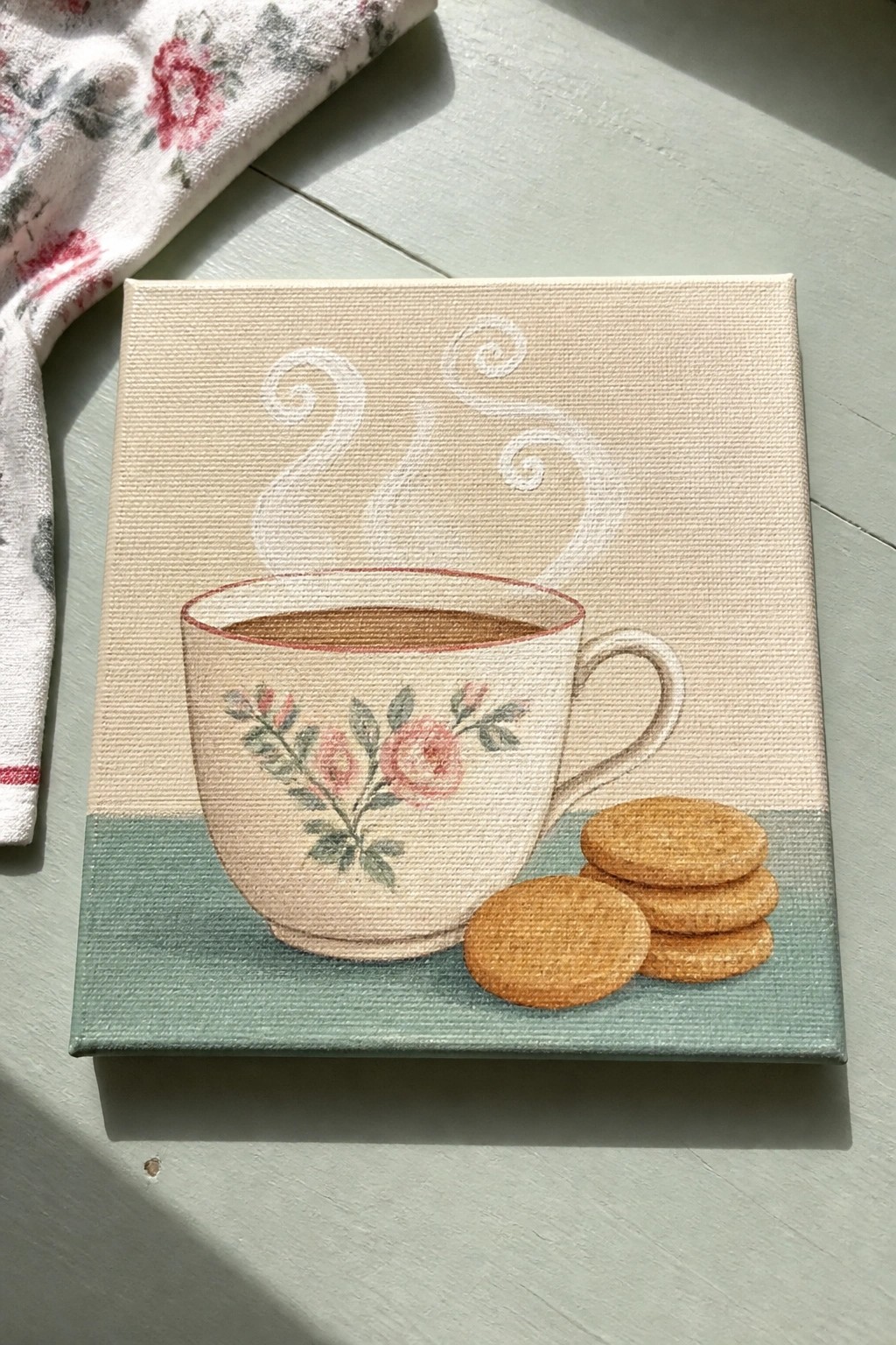 Canvas painting of floral teacup with steam and three cookies on table
