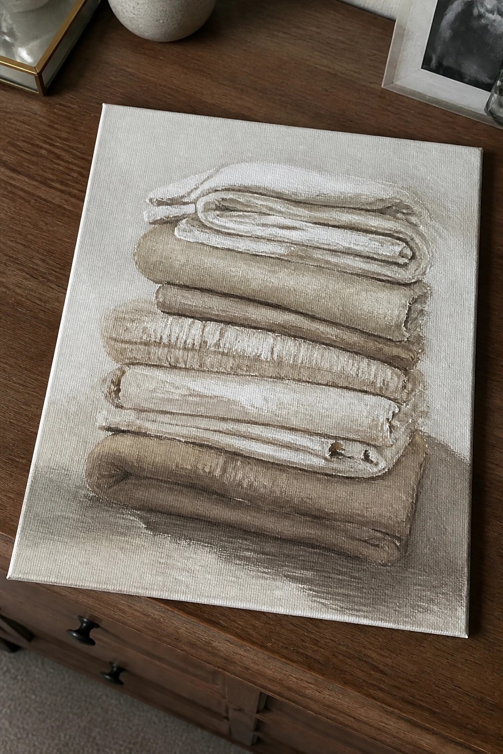 Textured painting of stacked beige and white folded towels on canvas