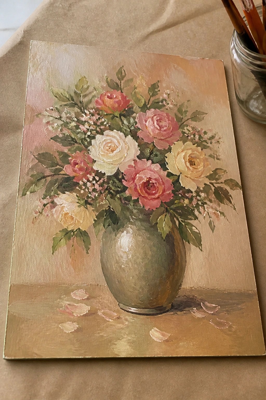 Oil painting of pink, white, and yellow roses in green vase with fallen petals