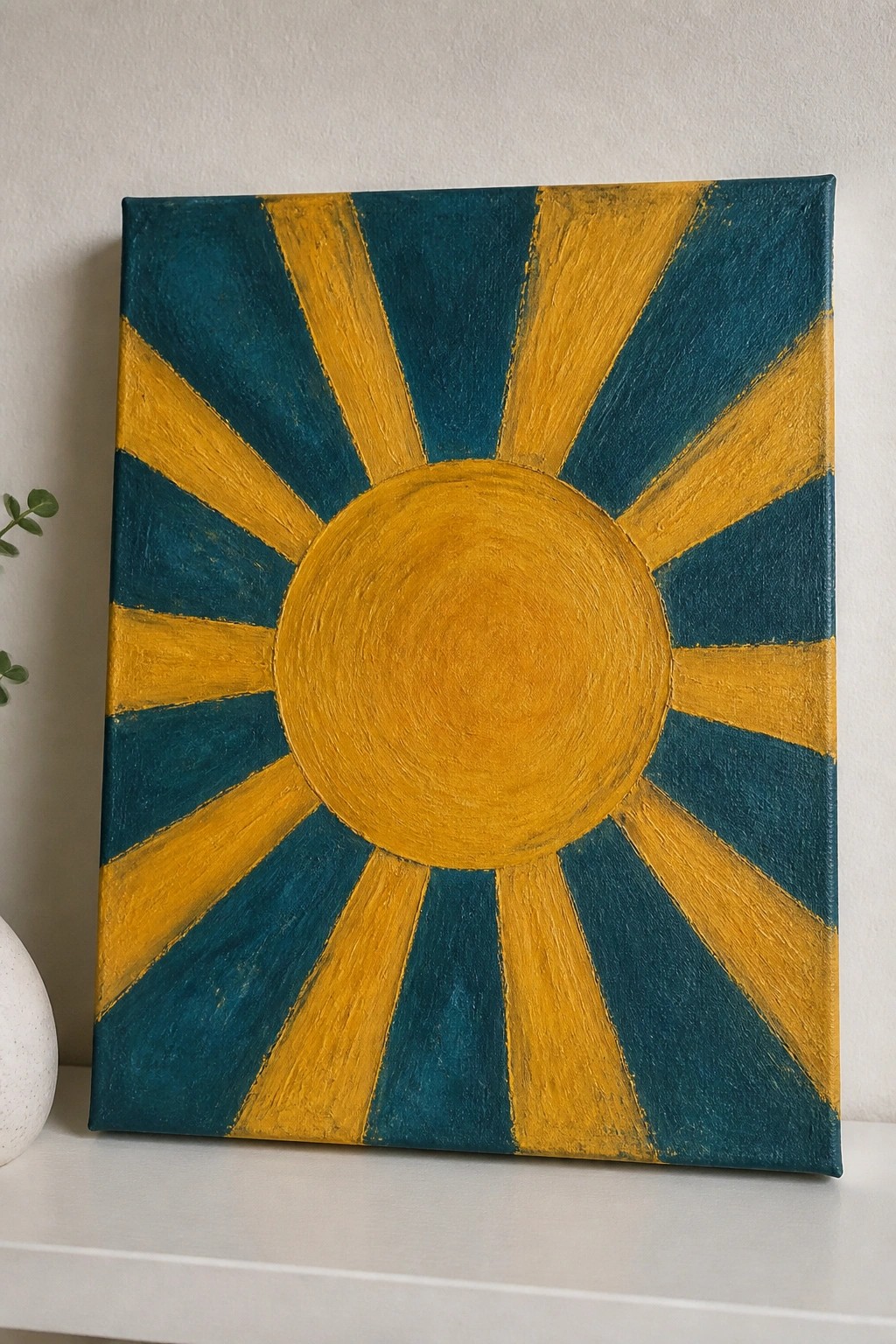 Yellow sun with teal rays on square canvas against white wall