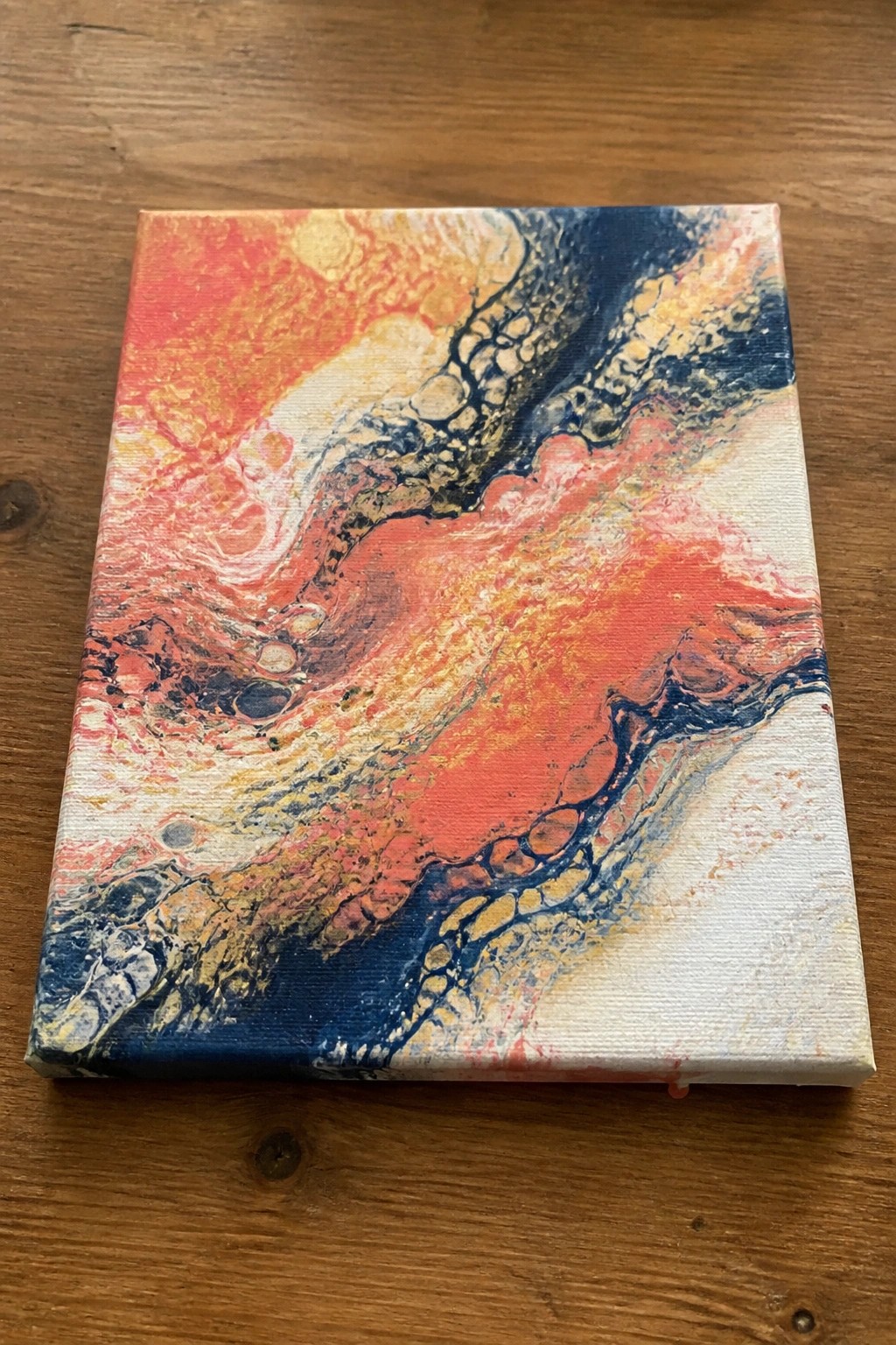 Abstract fluid art painting on canvas with swirling reds, oranges, blues, and yellows.