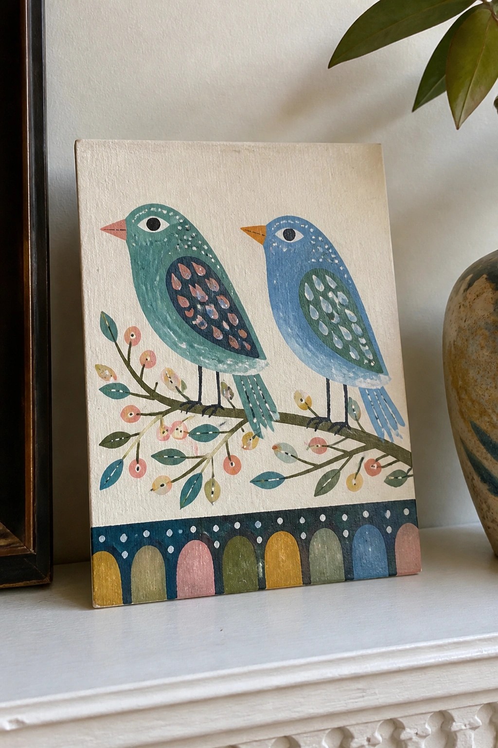 Two stylized birds on a berry branch above a colorful arched border in folk art painting.
