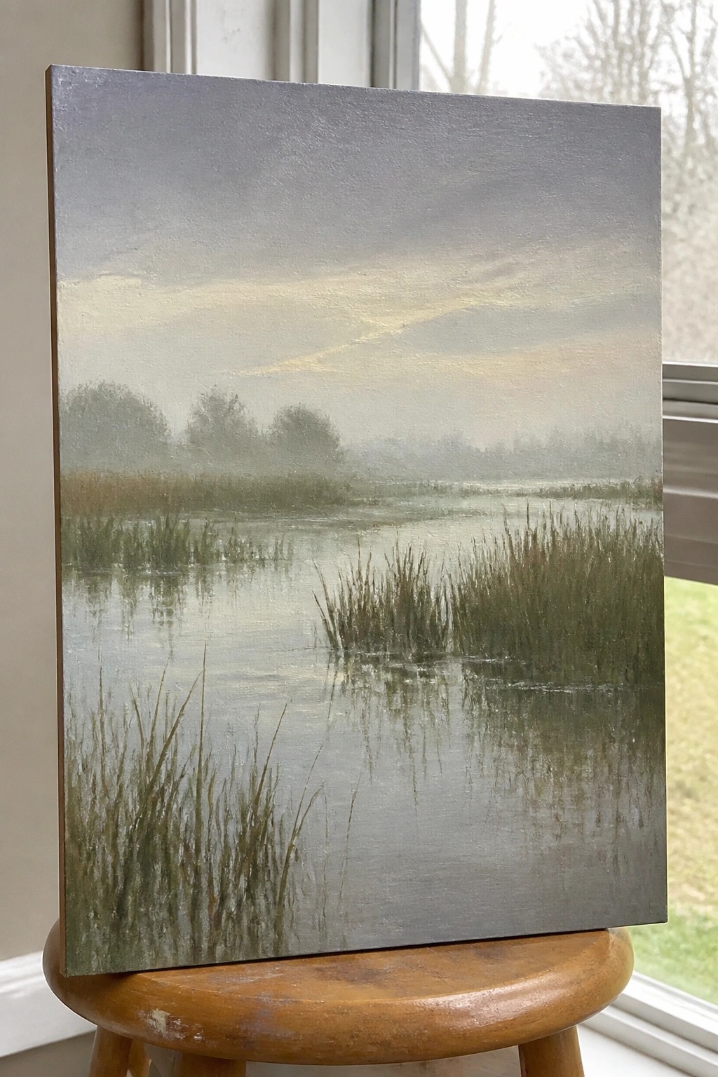 Misty wetland painting with tall reeds reflecting in calm water on wooden stool