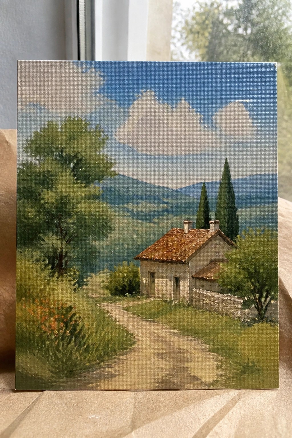 Rustic stone house with tiled roof beside dirt path amid green hills under blue sky.