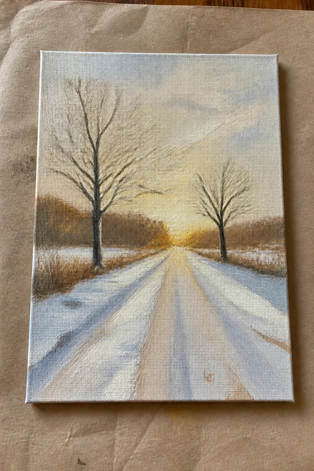 Winter canvas painting of snowy road with bare trees at glowing sunset