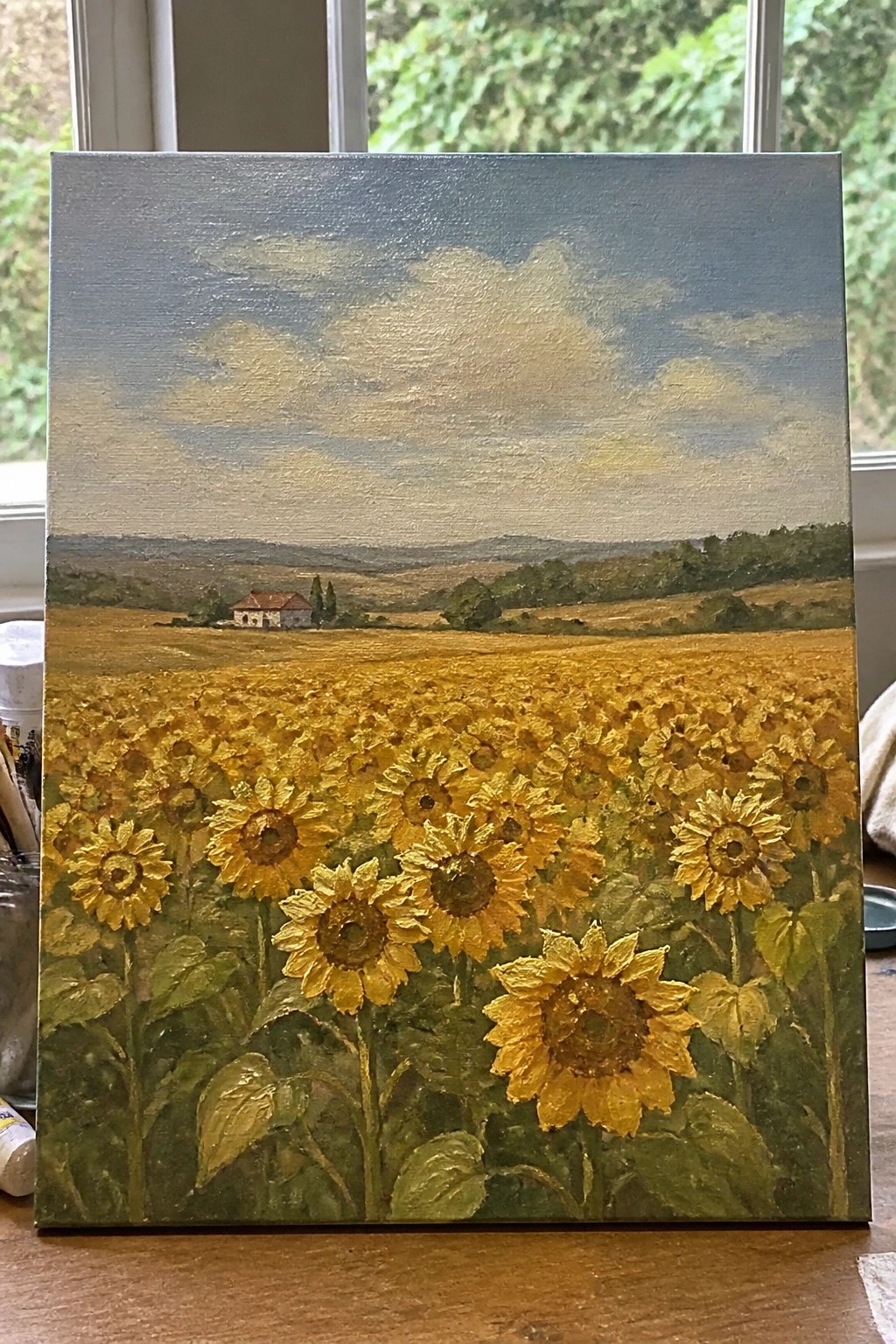 Vivid oil painting of blooming yellow sunflowers in golden field with distant house and hills.