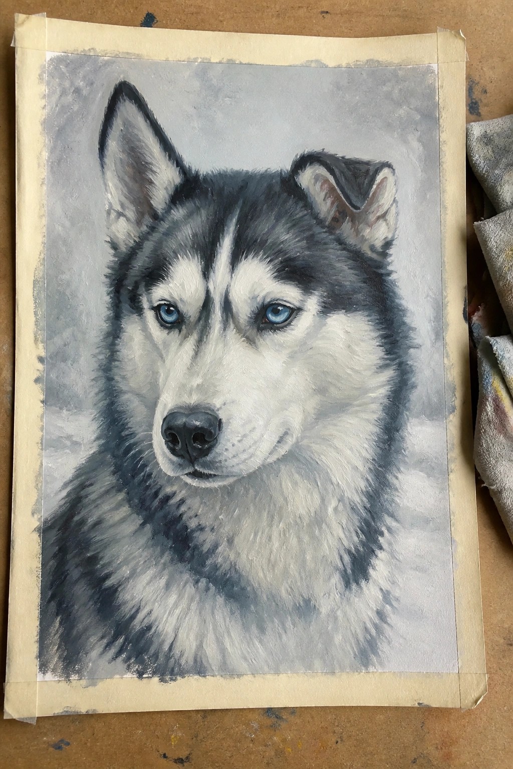 Realistic painting of a black and white husky with striking blue eyes on paper