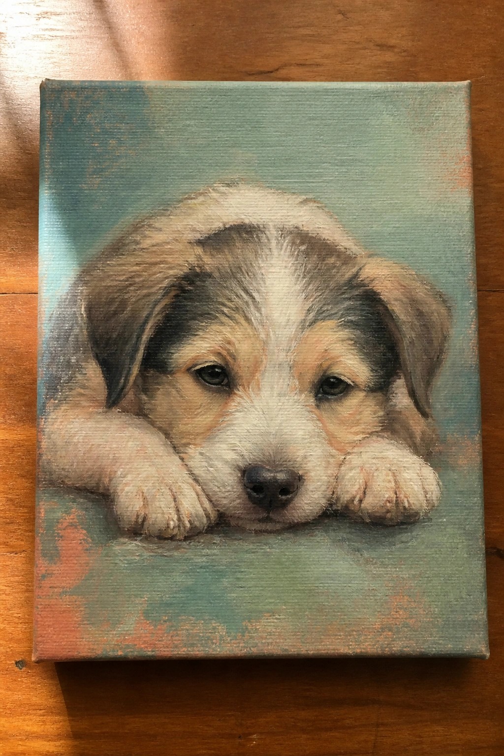 Realistic painting of a brown and white puppy resting its head on teal canvas