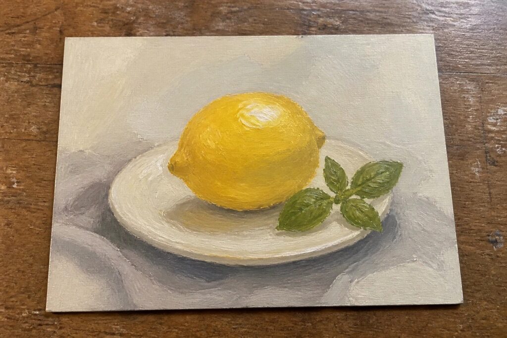 Yellow lemon and basil leaves on white plate over light gray cloth