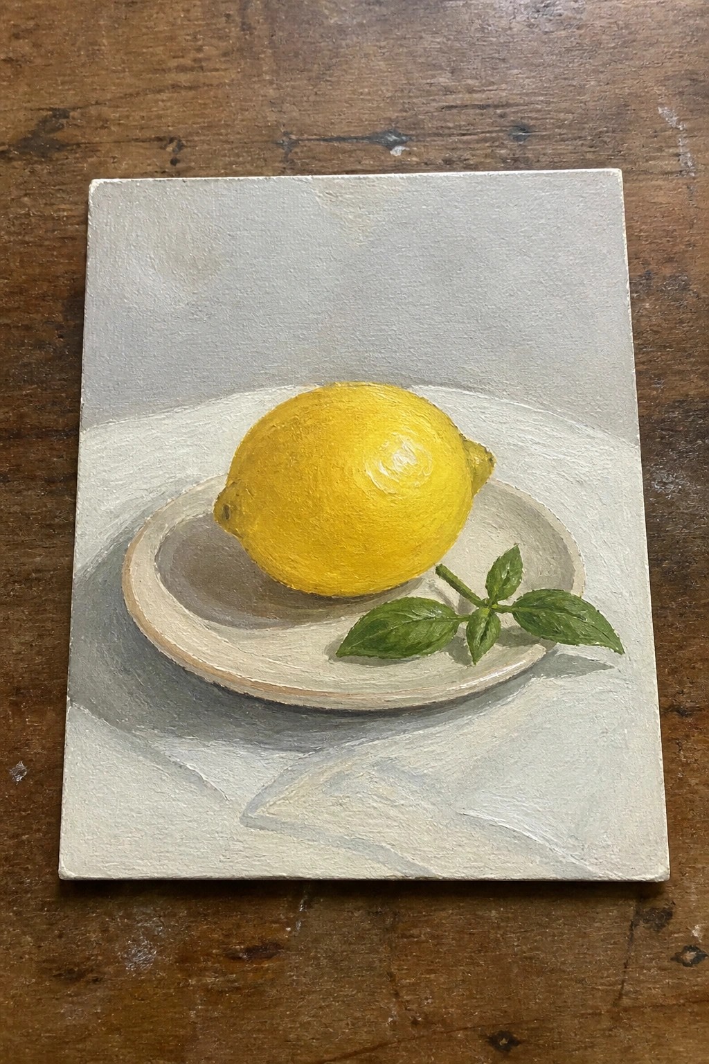 Yellow lemon and basil leaves on white plate over light gray cloth