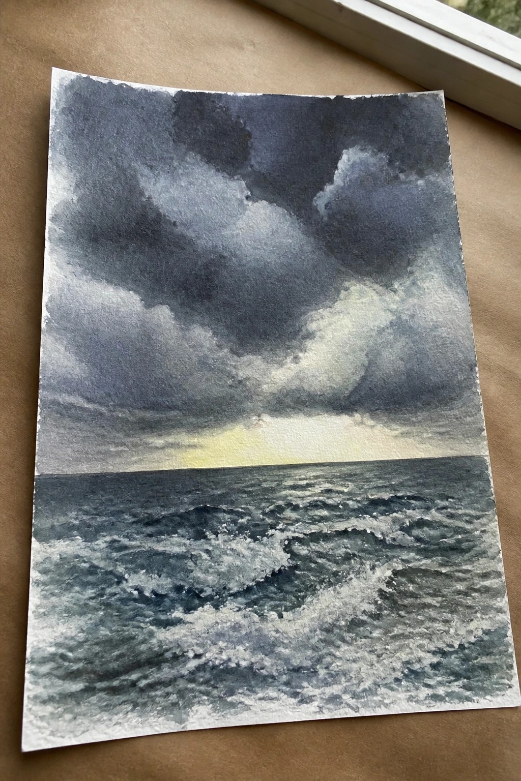 A watercolor painting of a dark stormy ocean with heavy clouds and a bright spot of sunlight on the horizon.