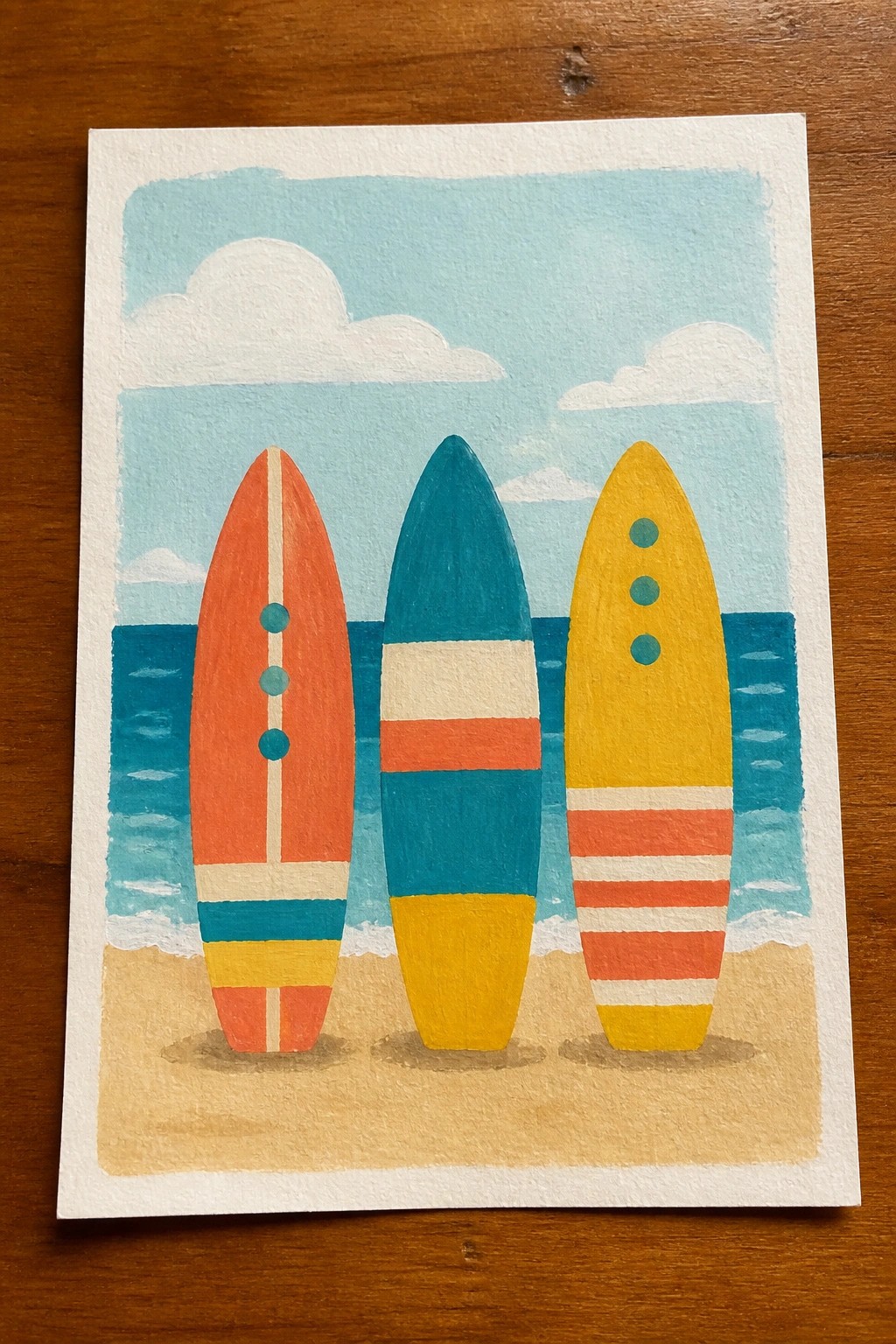 Three colorful surfboards standing in sand by ocean waves under blue sky.